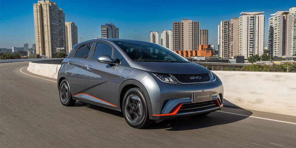 BYD Dolphin electric hatchback driving in urban environment, compact EV with sporty front fascia and dynamic city performance