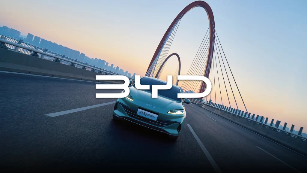 BYD Seal 06 electric sedan driving on city bridge at sunset, aerodynamic EV design with LED headlights and dynamic performance styling